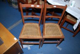 Two kitchen chairs with cane seats.