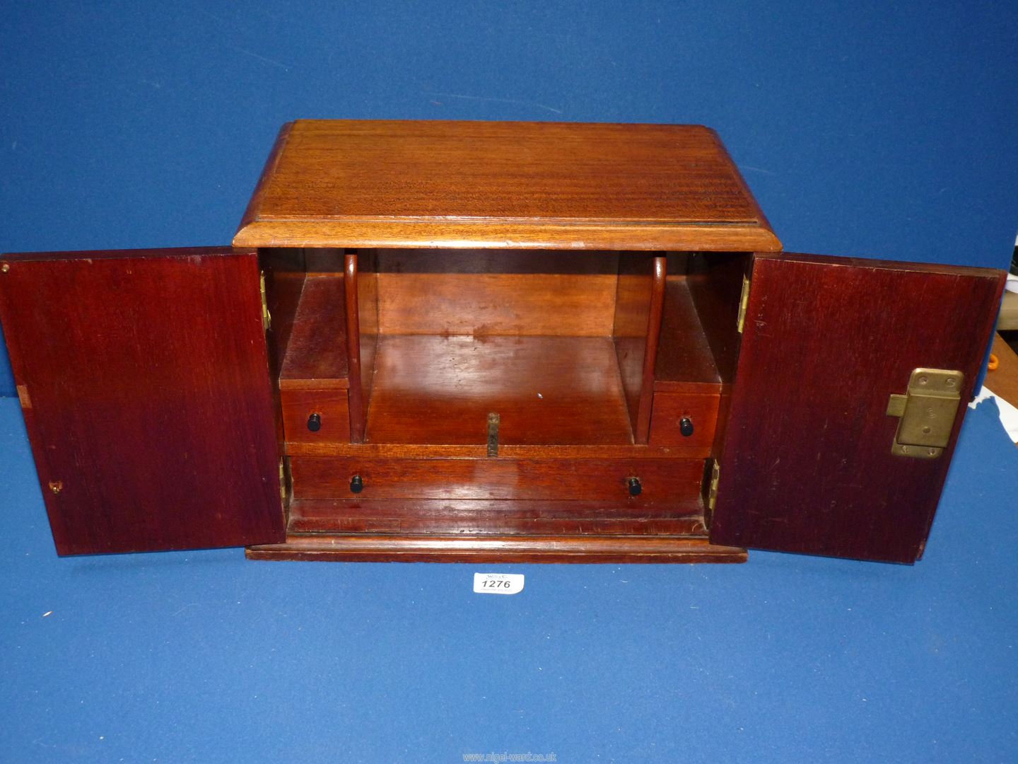 A smokers cabinet having lower drawer and two smaller drawers to the side with opening top and two