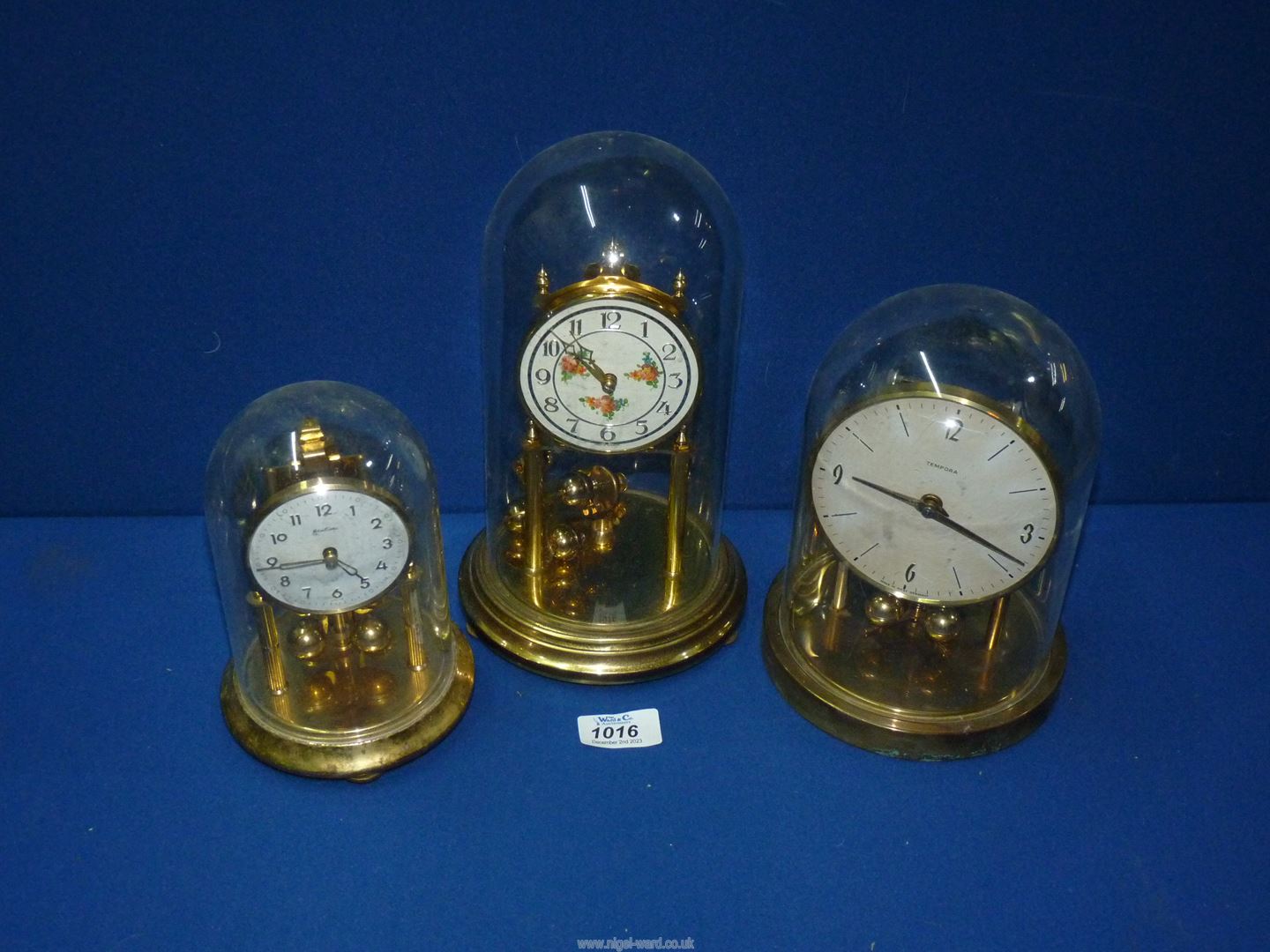 Three anniversary clocks including Bentime and Tempora, one with glass dome, two with plastic.