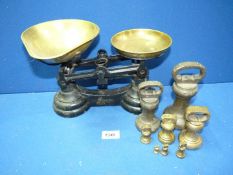 A set of Weighing scales with brass pans and various brass weights including 2lb and 4lb weights.