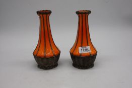 A pair of antique continental orange glass vases which are encased in woven metal basket effect,