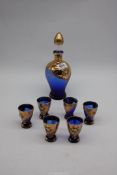 A blue glass decanter set with gold and painted floral detail.