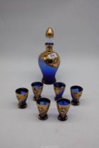 A blue glass decanter set with gold and painted floral detail.