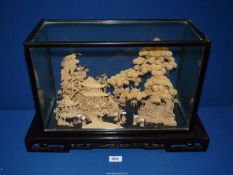 An oriental Cork diorama with house and surrounding trees in a glass case,