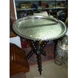 A Benares table with white metal engraved circular top fixed onto a bobbin tripod base,