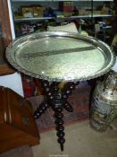 A Benares table with white metal engraved circular top fixed onto a bobbin tripod base,