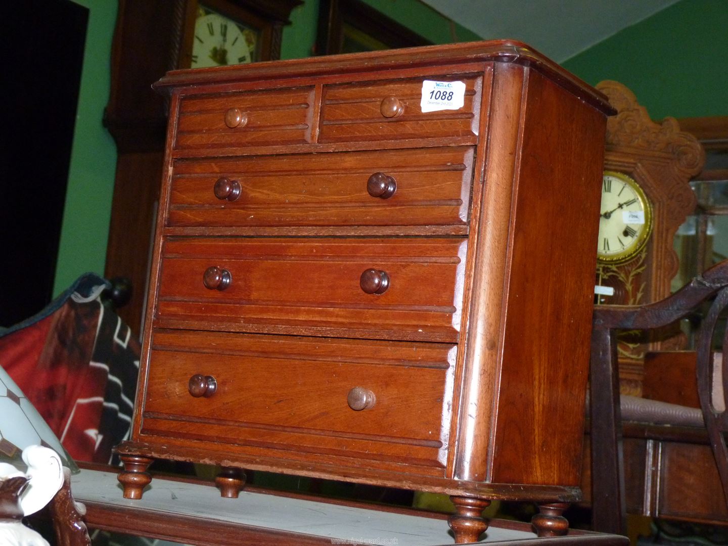 A 19th century miniature oak chest of two short and three long graduated drawers standing on turned