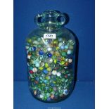 A large quantity of marbles in a glass demijohn.