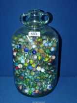 A large quantity of marbles in a glass demijohn.