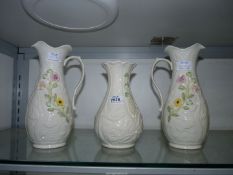 Two Belleek jugs with floral detail and a vase with Shamrock pattern.