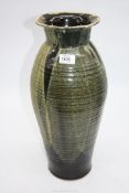 A tall heavy Studio Pottery vase in green drip glaze with ribbed effect, black interior glaze,