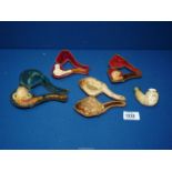 A small tray containing four carved meerschaum pipes/cheroot holders to include; stag, maiden,