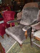 An Edwardian open armed fireside Chair standing on turned front legs and upholstered in brown