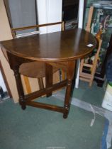 An unusual Oak demi-lune Table having a rear drop-leaf with a gateleg and standing on turned legs