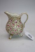 A porcelain Cream Jug standing on three legs, painted with roses and gilded enhancement,