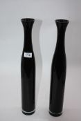 A pair of tall slender black glass vases with narrow necks and thick clear bases,
