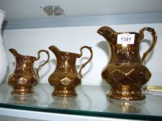 A set of three graduated Wade gold Lustre jugs.