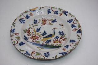 An English Delft Charger decorated with a heron and trailing plants.