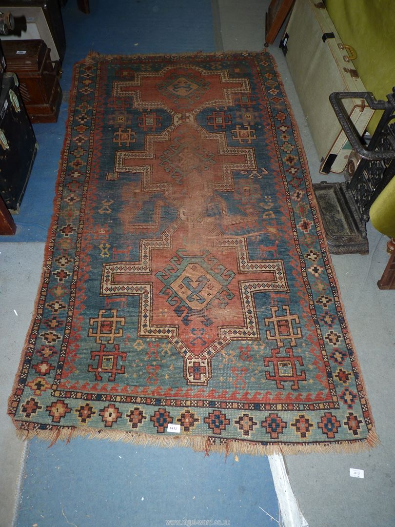 A border pattern rug in blue ground with red and cream geometric patterns, worn condition,