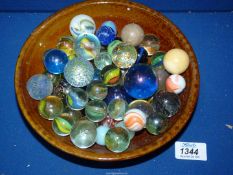 A quantity of large marbles in a pottery bowl.