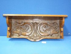 A carved wood wall shelf with stylised fish and foliage decoration,