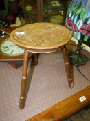 A mixed hardwoods arts and crafts dished circular seated three legged Stool,
