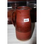 A russet red Studio Pottery jug with purple brush abstract marks to front,