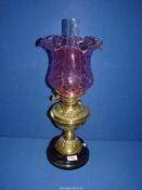 A Brass Oil Lamp having a cranberry glass shade and clear glass chimney.