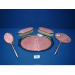 A vintage dressing table set in pink enamel comprising tray, two clothes brushes,