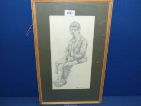 A framed and mounted Pencil sketch of a young man in a seated position, signed lower right J.