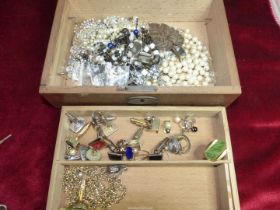 A wooden jewellery box containing vintage costume jewellery, including silver and other cufflinks.