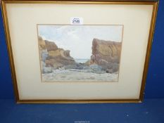 A framed and mounted watercolour of a coastal scene with precarious rocks on a beach,