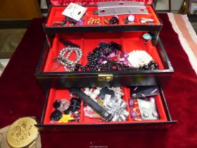 A black jewellery box and contents including costume beads, earrings, etc.