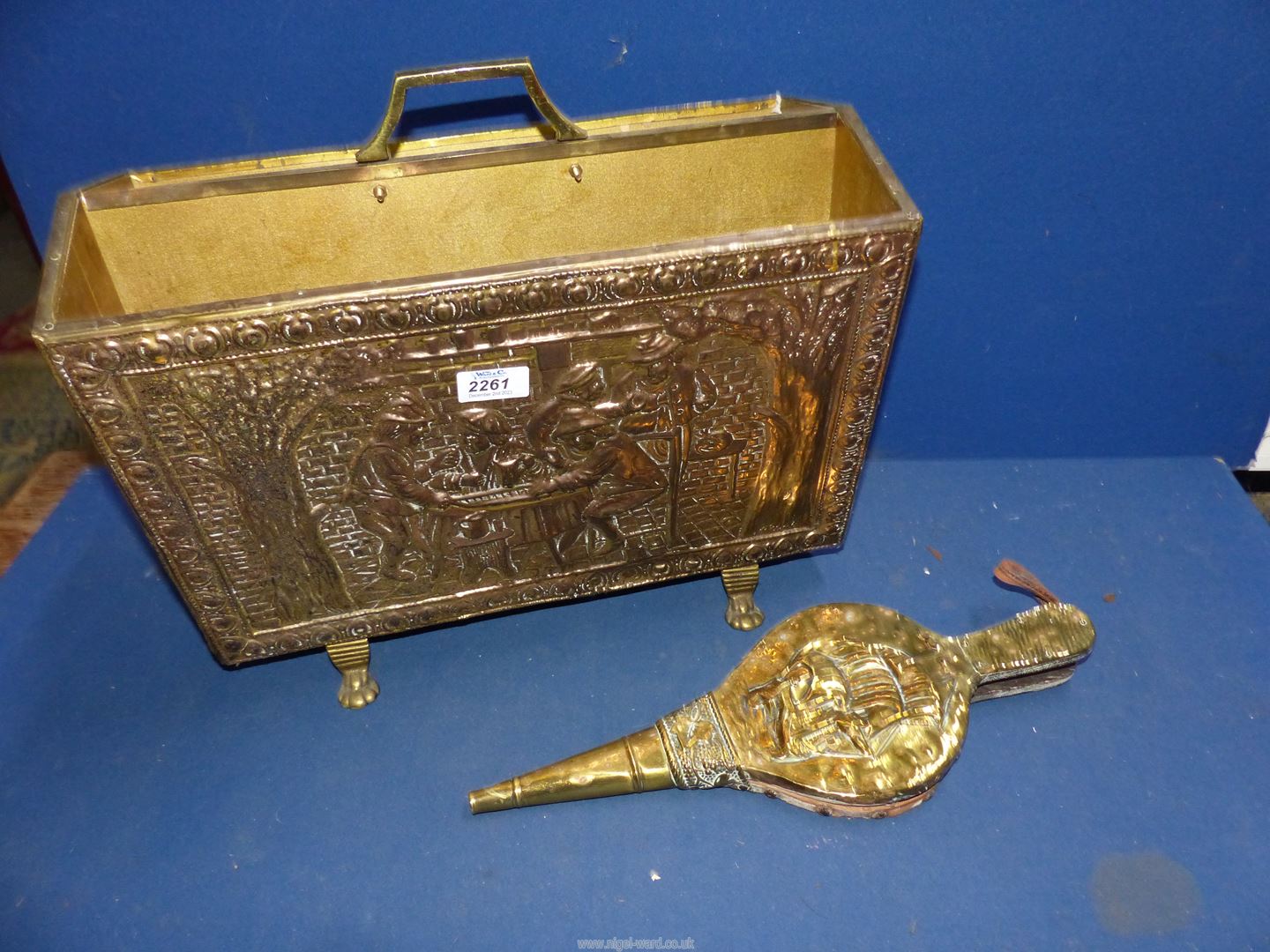 A brass magazine rack with embossed tavern scenes, together with a pair of brass coated bellows.