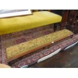 An antique footstool with tapestry cover