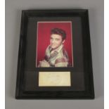 A framed Elvis Presley photograph with signature. Dimensions including frame 25cm x 33.5cm.