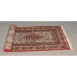 A floral red and cream ground wool runner featured tasseled edges.