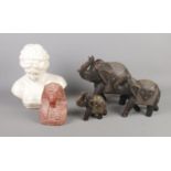A quantity of figures including stone bust of Tutankhamun, trio of carved wooden elephants and
