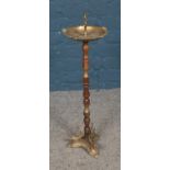 A brass and turned wood ash tray stand with engraved decoration depicting a fishing scene.