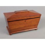 A mahogany triple tea caddy in sarcophagus form raised small ball feet.