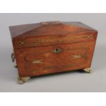 A Regency tea caddy of sarcophagus form. With cut glass bowl, brass lion paw feet, inlaid brass