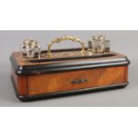 A walnut, mahogany and ebonised desk tidy, with brass handle, two inkwells and lower pen draw.