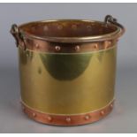 A brass and copper coal bucket with swing handle.