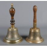 Two vintage brass school bells with turned wooden handles.