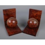 A pair of carved walnut bookends formed as cricket balls.