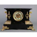 A large black slate mantle clock, with Roman Numeral dial, raised on scrolled gilt metal feet and