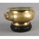 An oriental style, possibly Chinese, brass censor on stand featuring animal head twin handles.