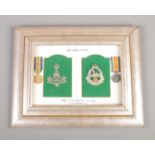 A framed set of Yorkshire and Lancashire military cap badges mounted along with miniature medal