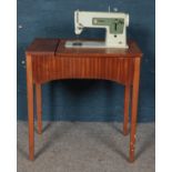 A teak sewing table, containing Singer sewing machine.