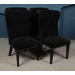 Four black button back dining chairs with studded edges and lion pull handle detail. Slits to one
